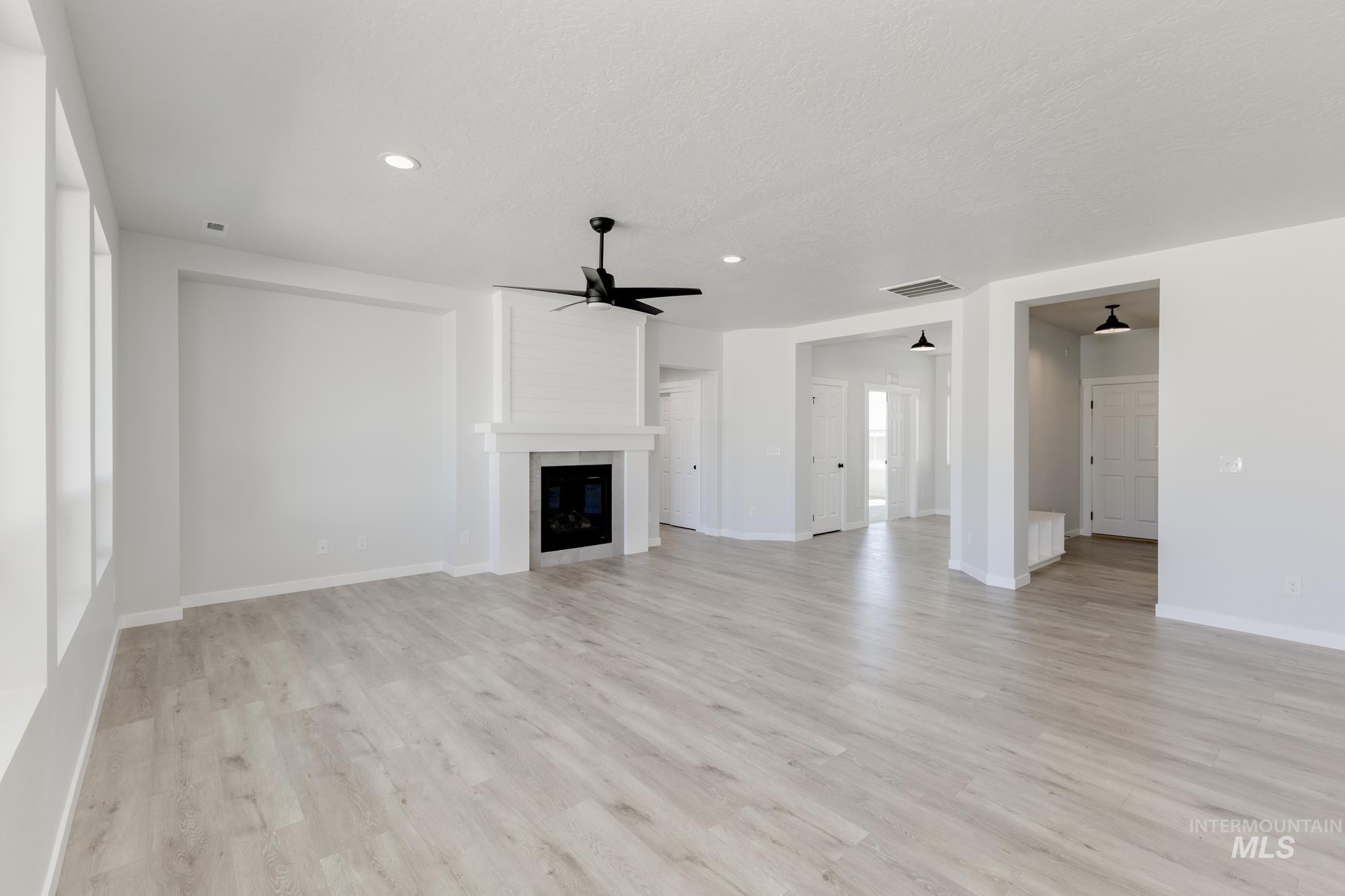 Unfurnished living room with light wood-style flooring, a fireplace, ceiling fan, and recessed lighting