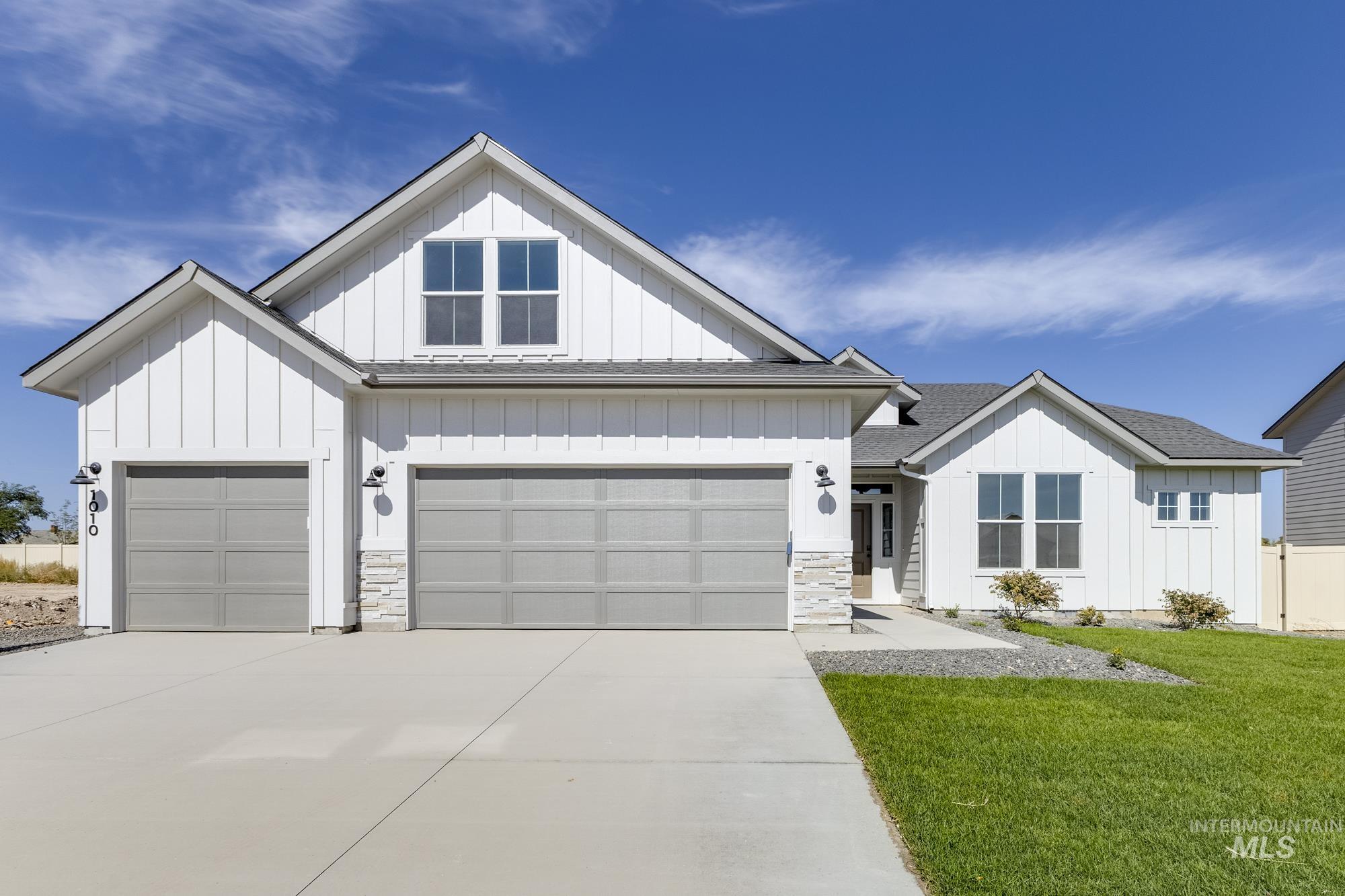 Modern farmhouse style home featuring board and batten siding, driveway, a front yard, a shingled roof, and a garage