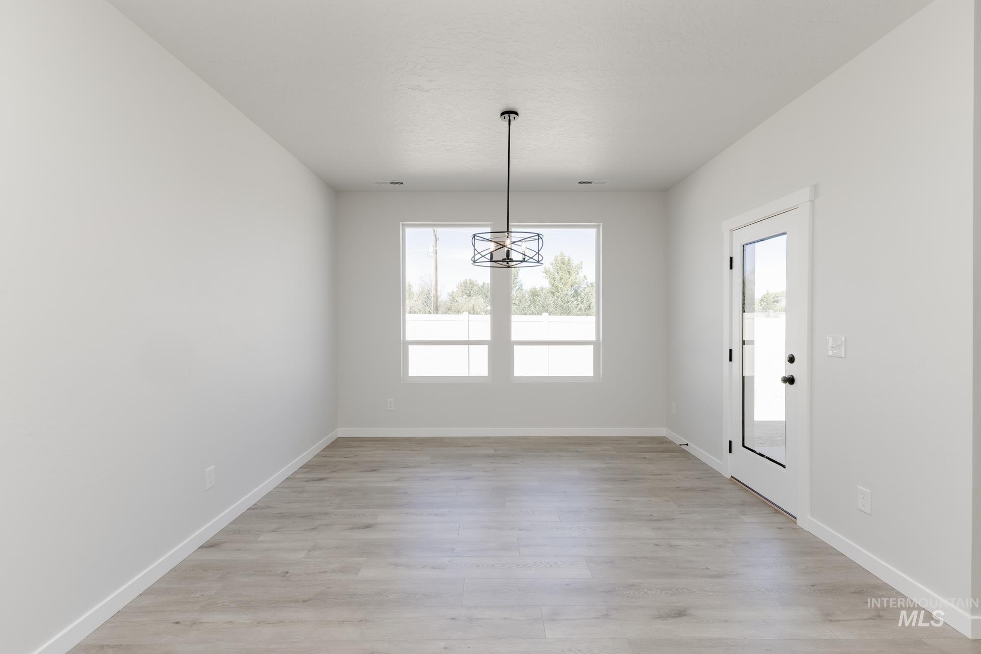 Unfurnished dining area featuring light wood finished floors and baseboards