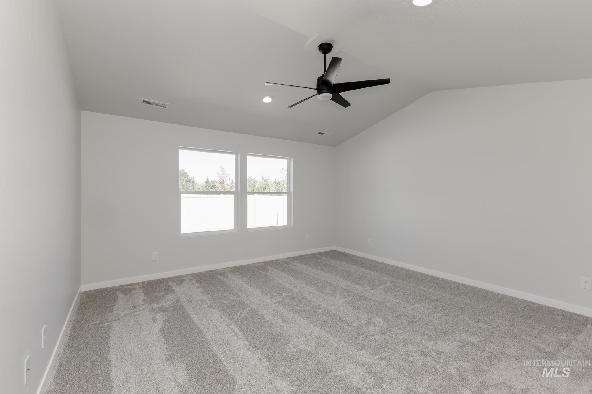 Empty room featuring vaulted ceiling, light carpet, a ceiling fan, and recessed lighting