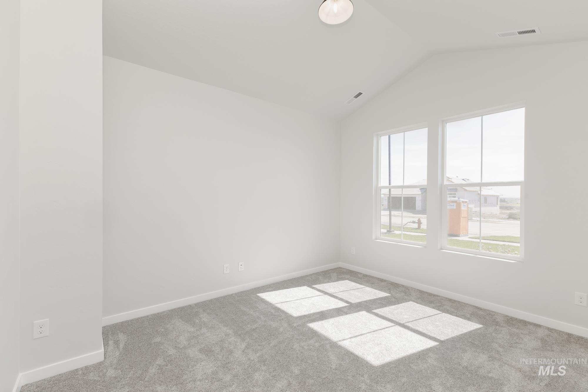Unfurnished room featuring carpet and lofted ceiling