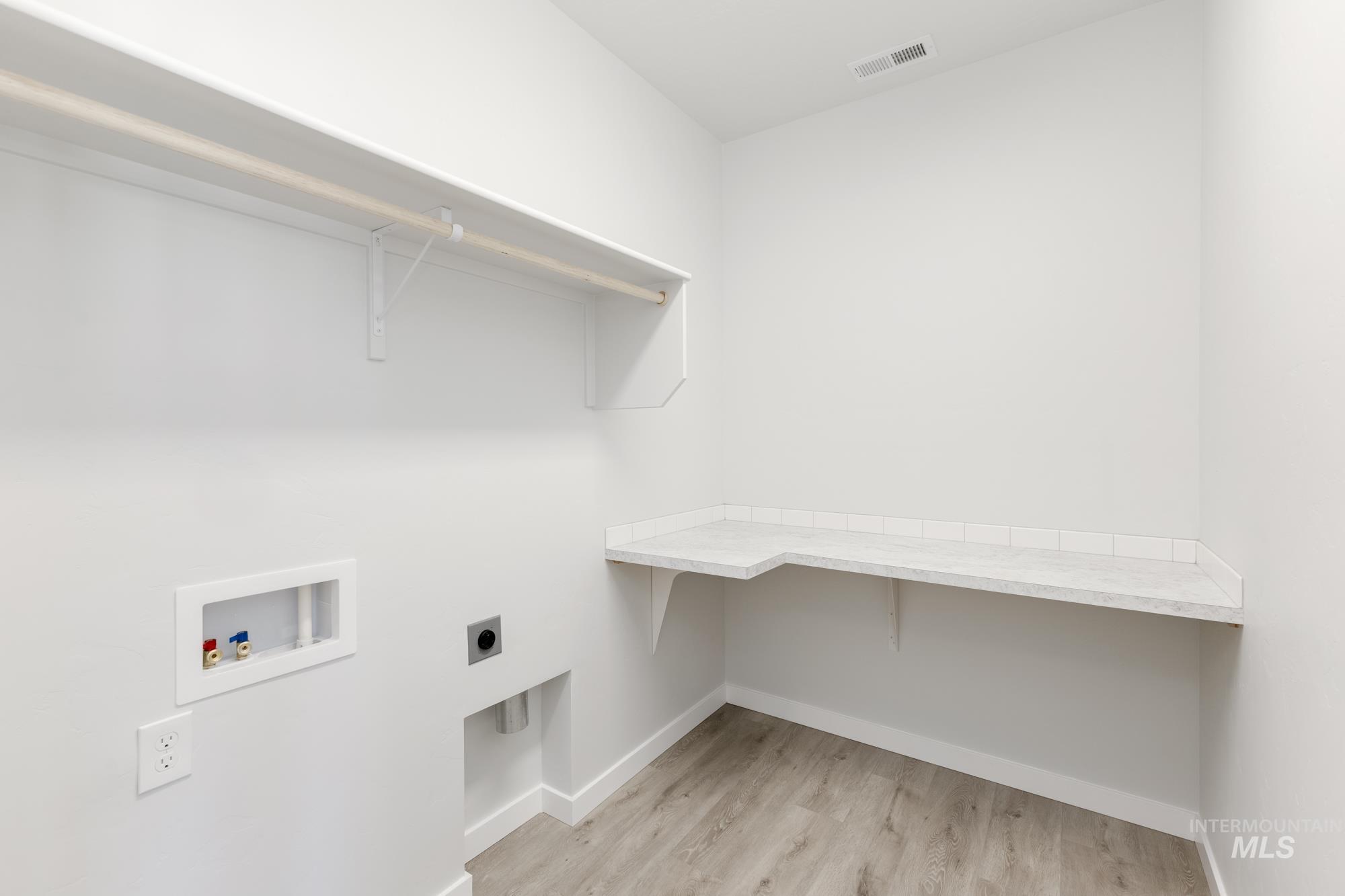 Laundry area with light wood-style flooring, hookup for a washing machine, and electric dryer hookup