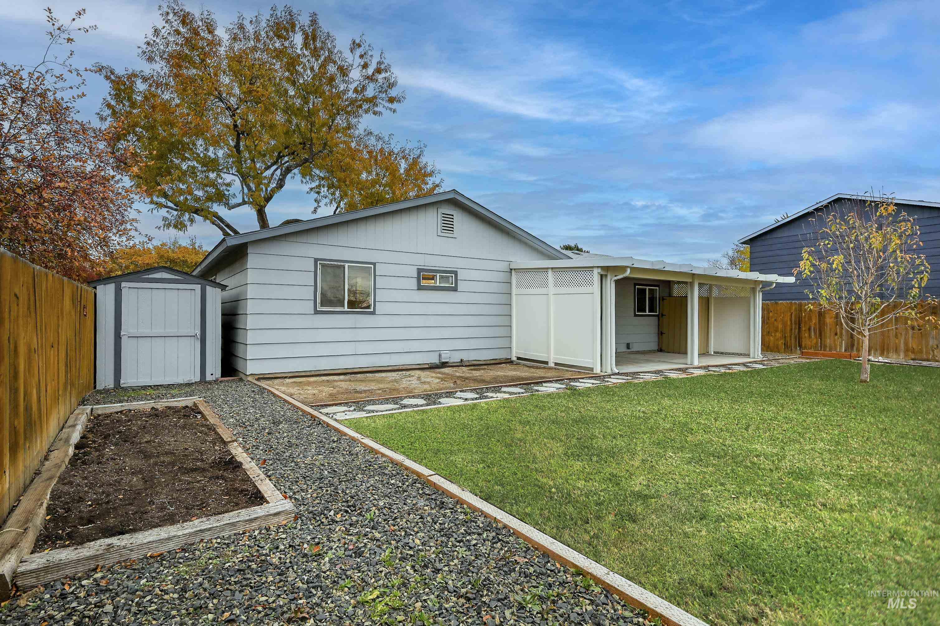 Rear view of house featuring a fenced backyard, a shed, a garden, and a patio