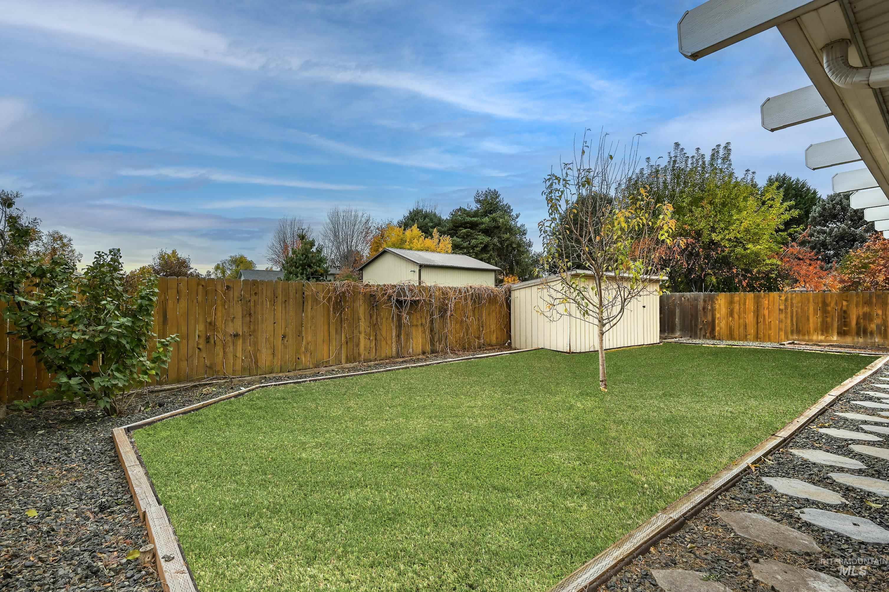 Fenced backyard featuring a storage unit
