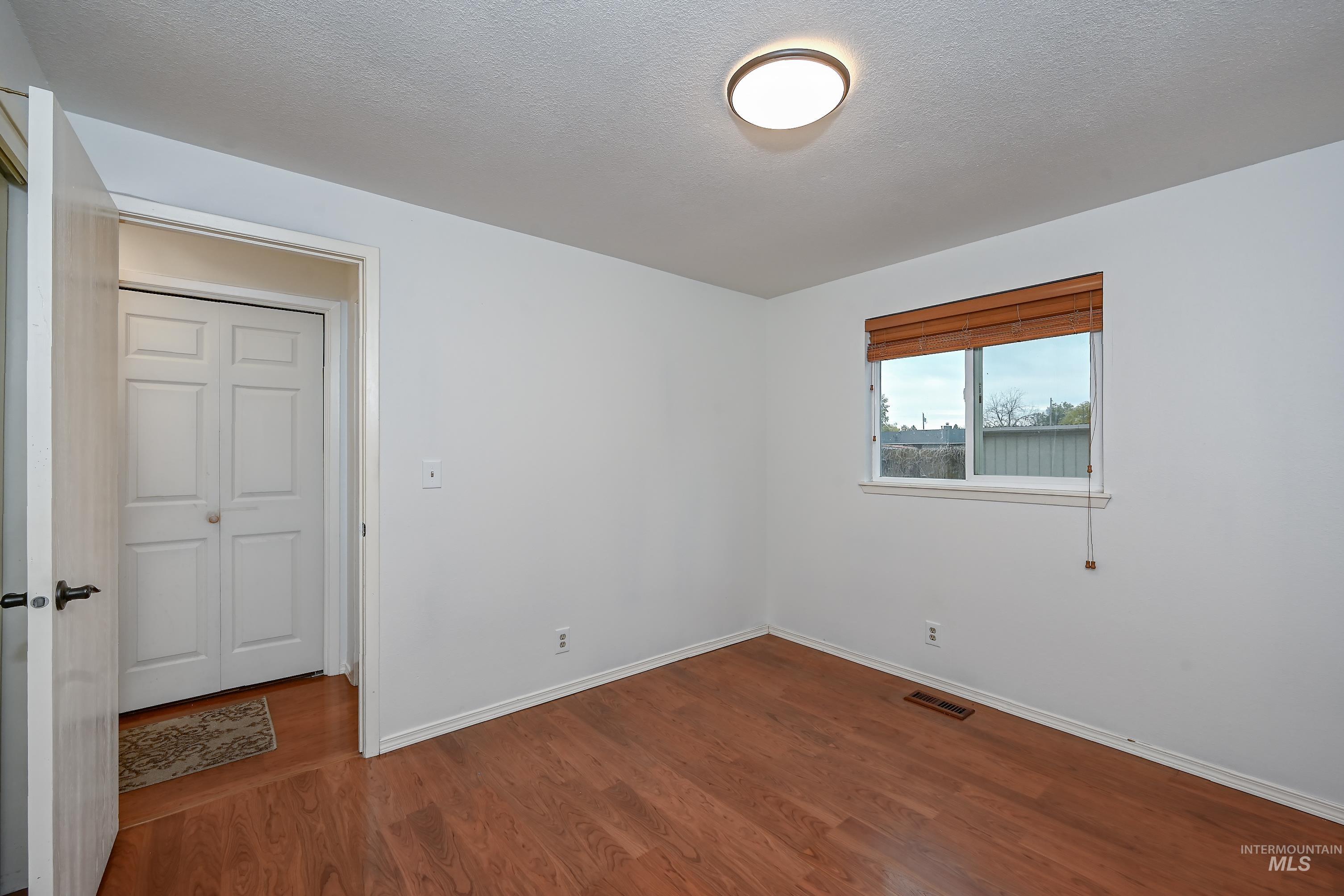 Empty room with a textured ceiling and dark wood-style floors