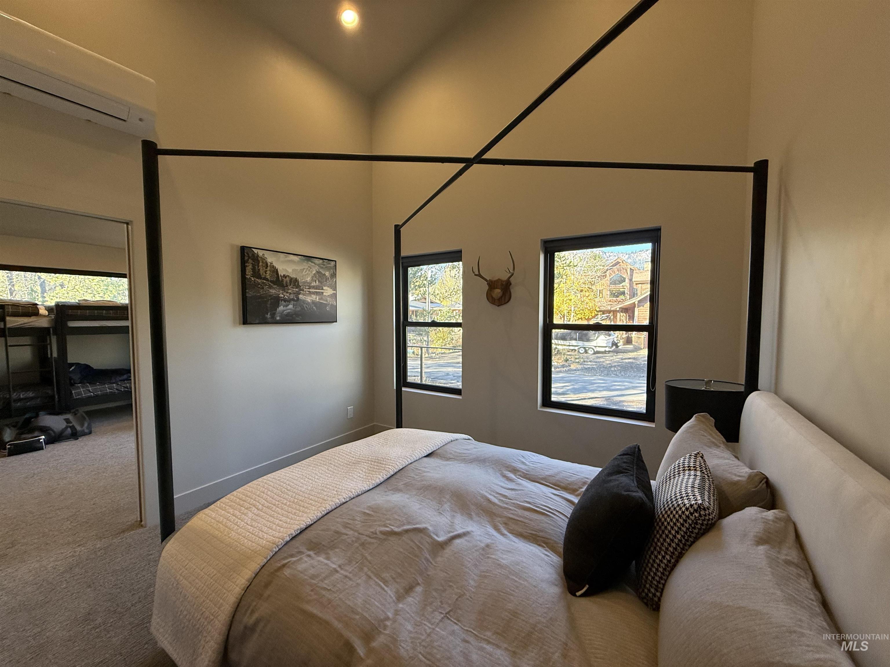Carpeted bedroom with a wall mounted mini split and recessed lighting