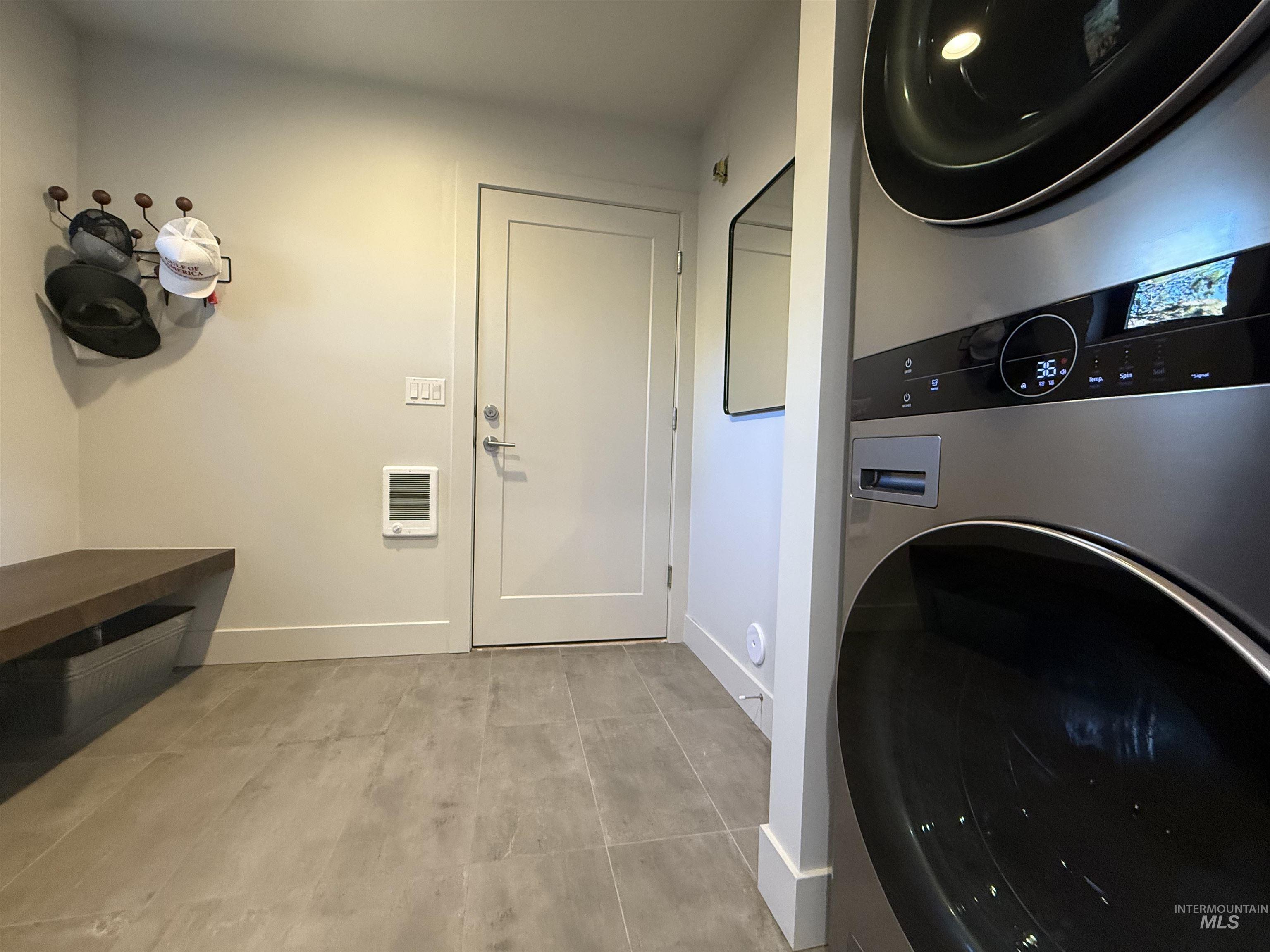 Laundry area with stacked washer and clothes dryer and heating unit