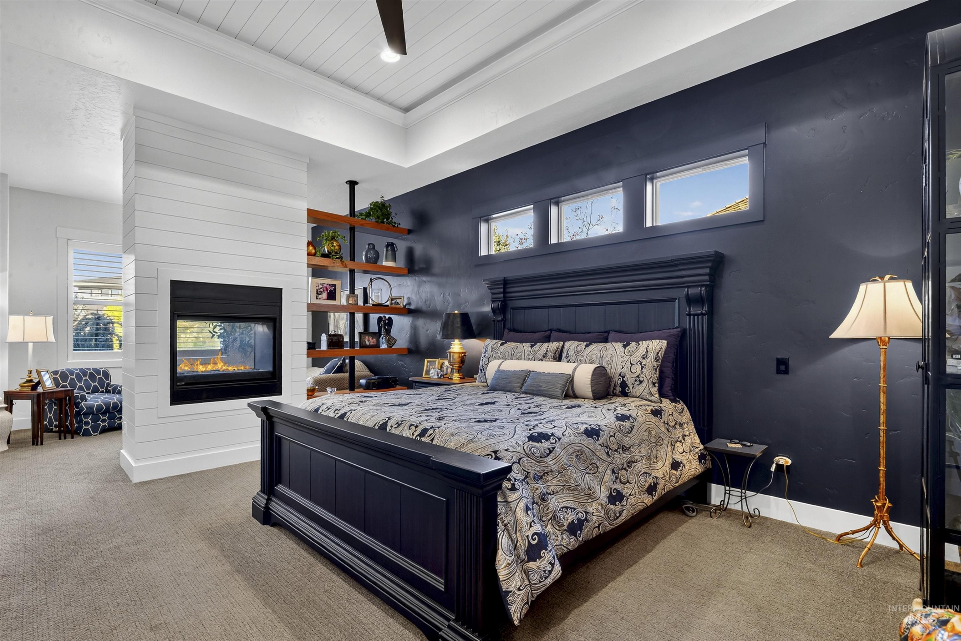 Carpeted bedroom with ornamental molding, a multi sided fireplace, and a ceiling fan