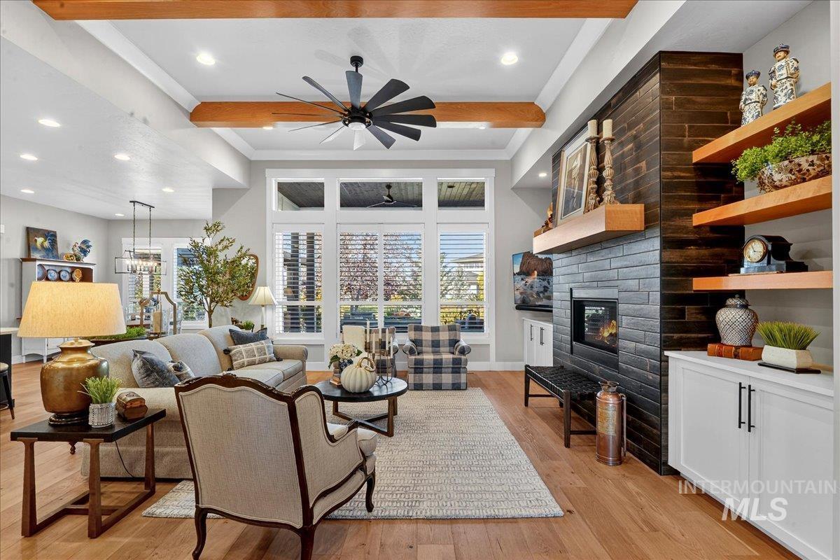 Living area with beam ceiling, light wood-type flooring, a large fireplace, healthy amount of natural light, and recessed lighting