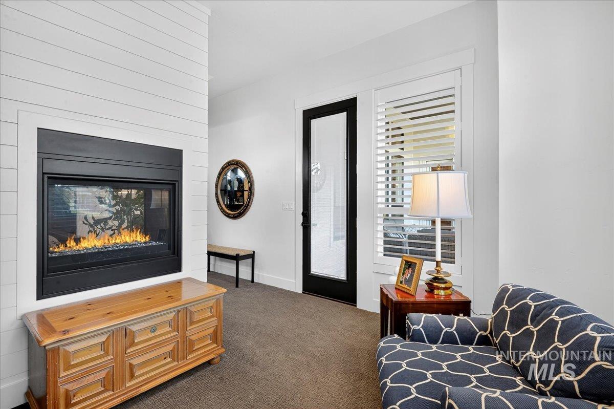 Living area featuring dark colored carpet and a glass covered fireplace