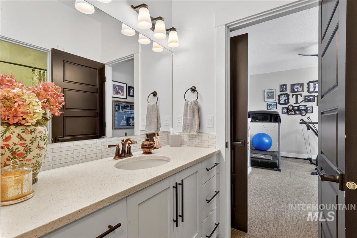 Bathroom with light carpet, vanity, and decorative backsplash