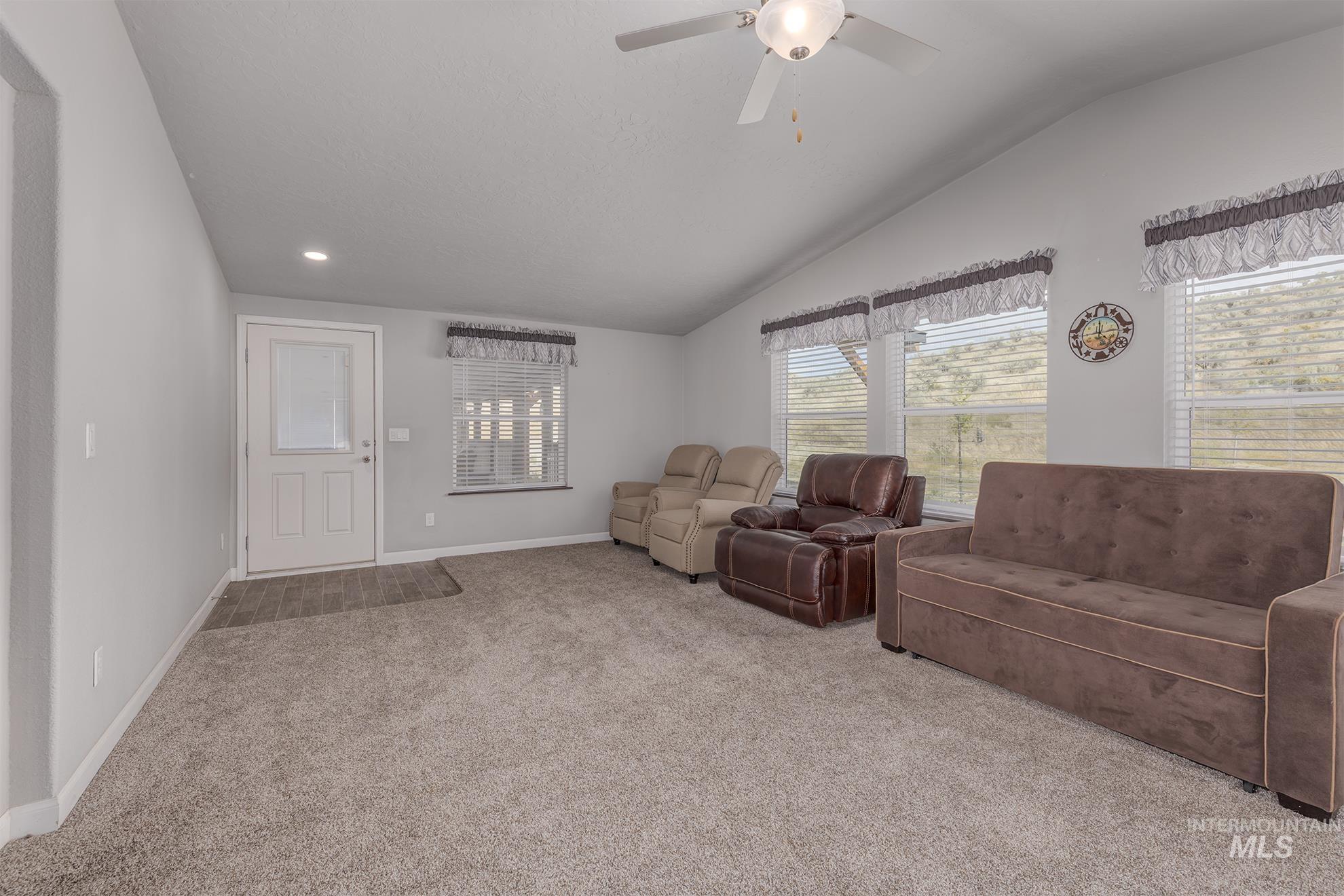 Carpeted living room featuring lofted ceiling and a ceiling fan