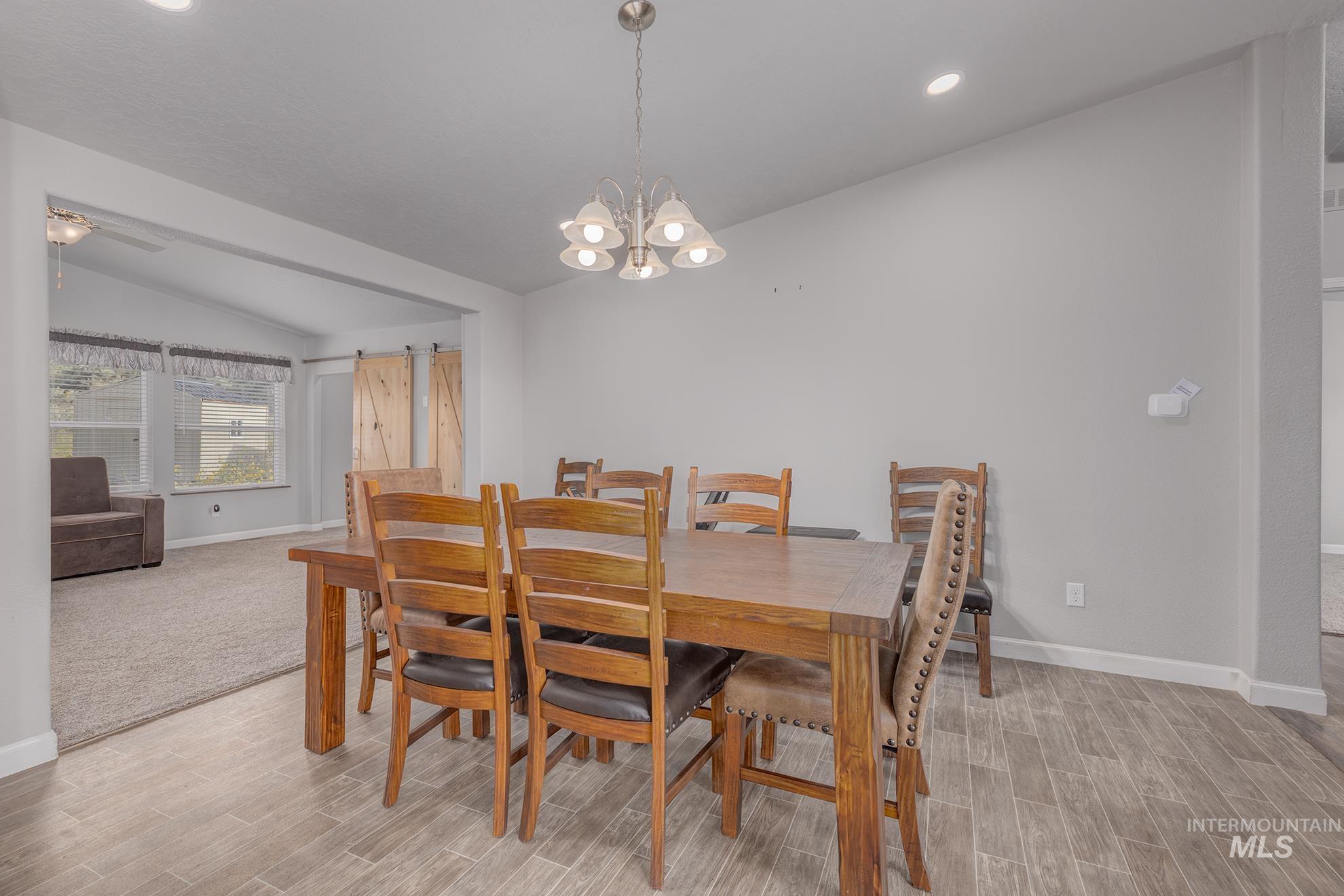 Dining area featuring vaulted ceiling, wood finish floors, a chandelier, and recessed lighting