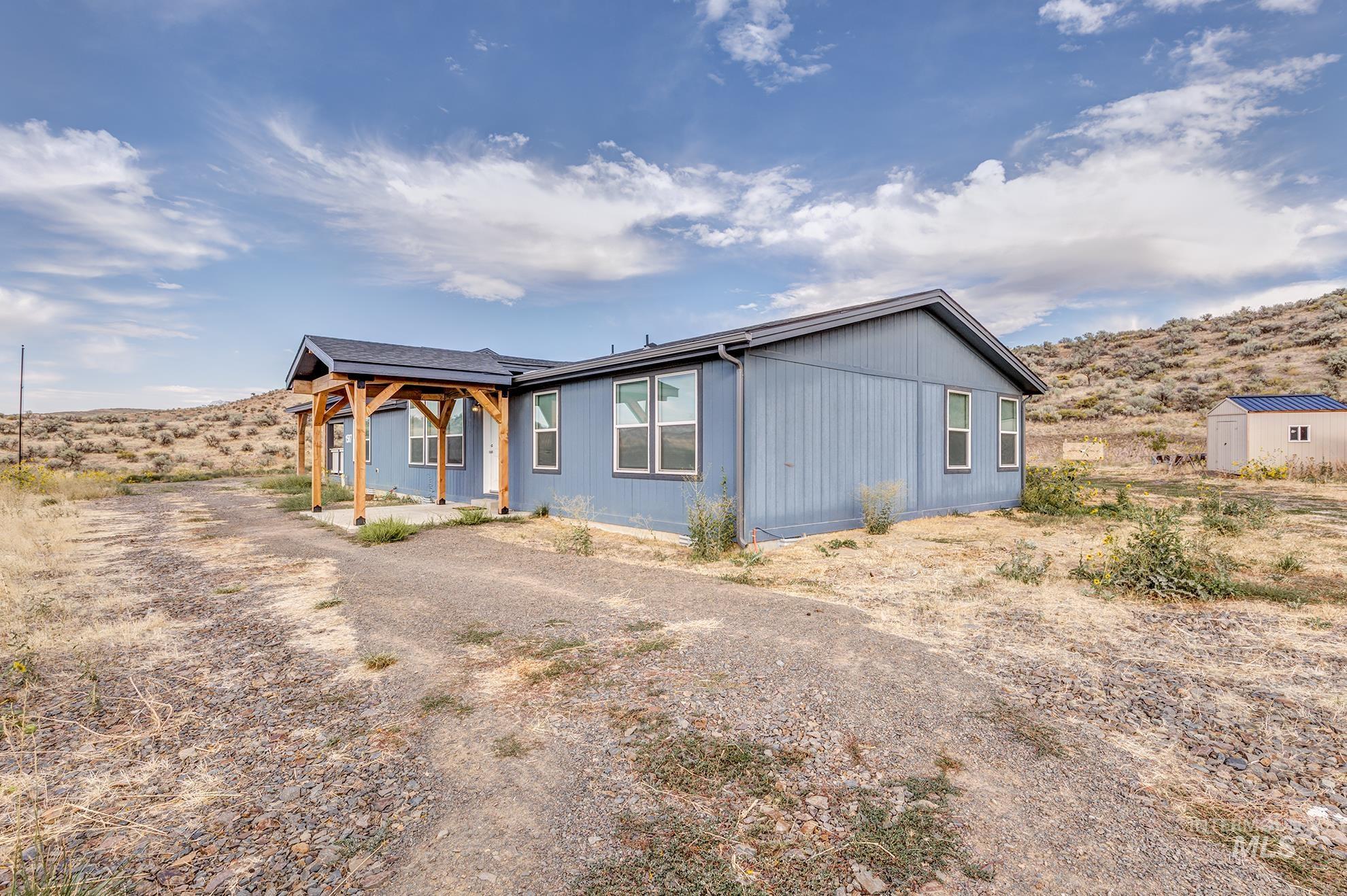 View of front of house featuring a patio area, a storage shed, and driveway