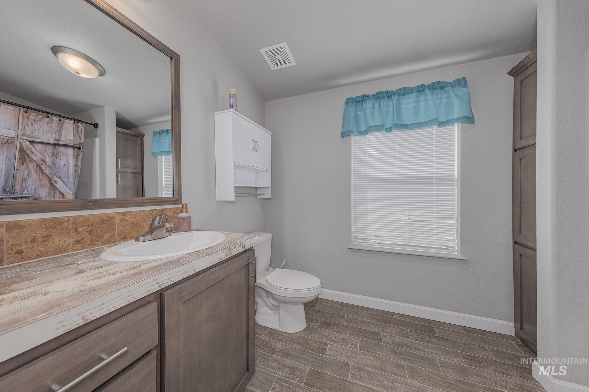 Full bathroom featuring vanity, wood finish floors, and a shower with shower curtain