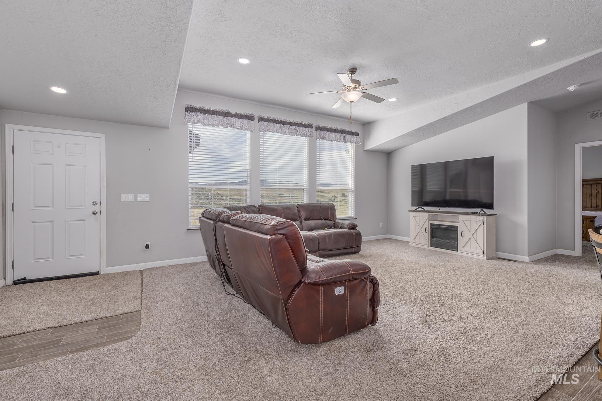 Living area featuring a textured ceiling, light carpet, recessed lighting, and ceiling fan