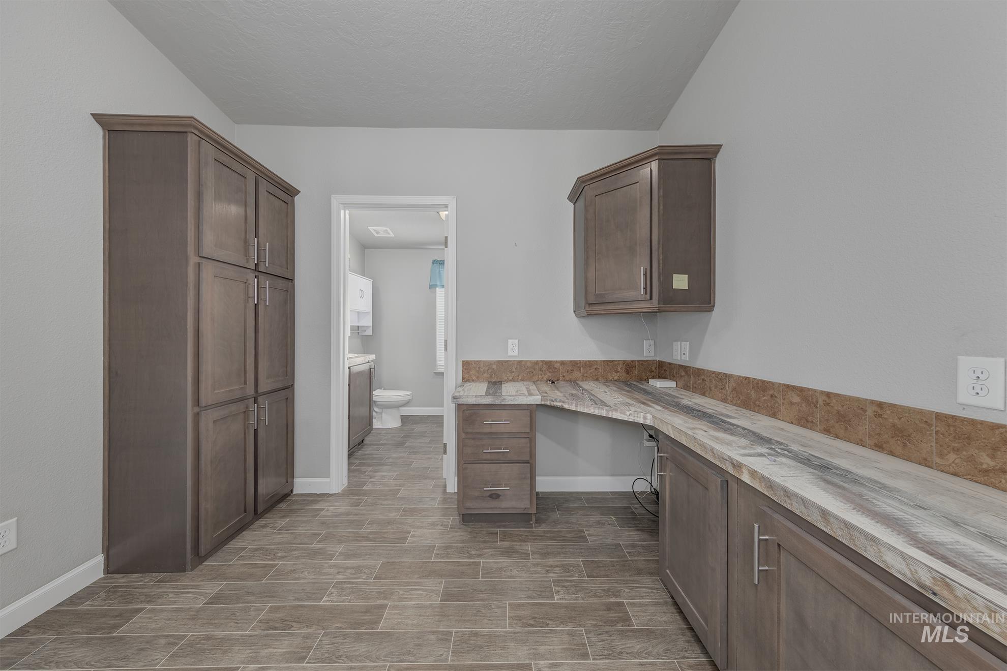 Kitchen featuring built in study area, dark brown cabinets, a textured ceiling, and wood finish floors