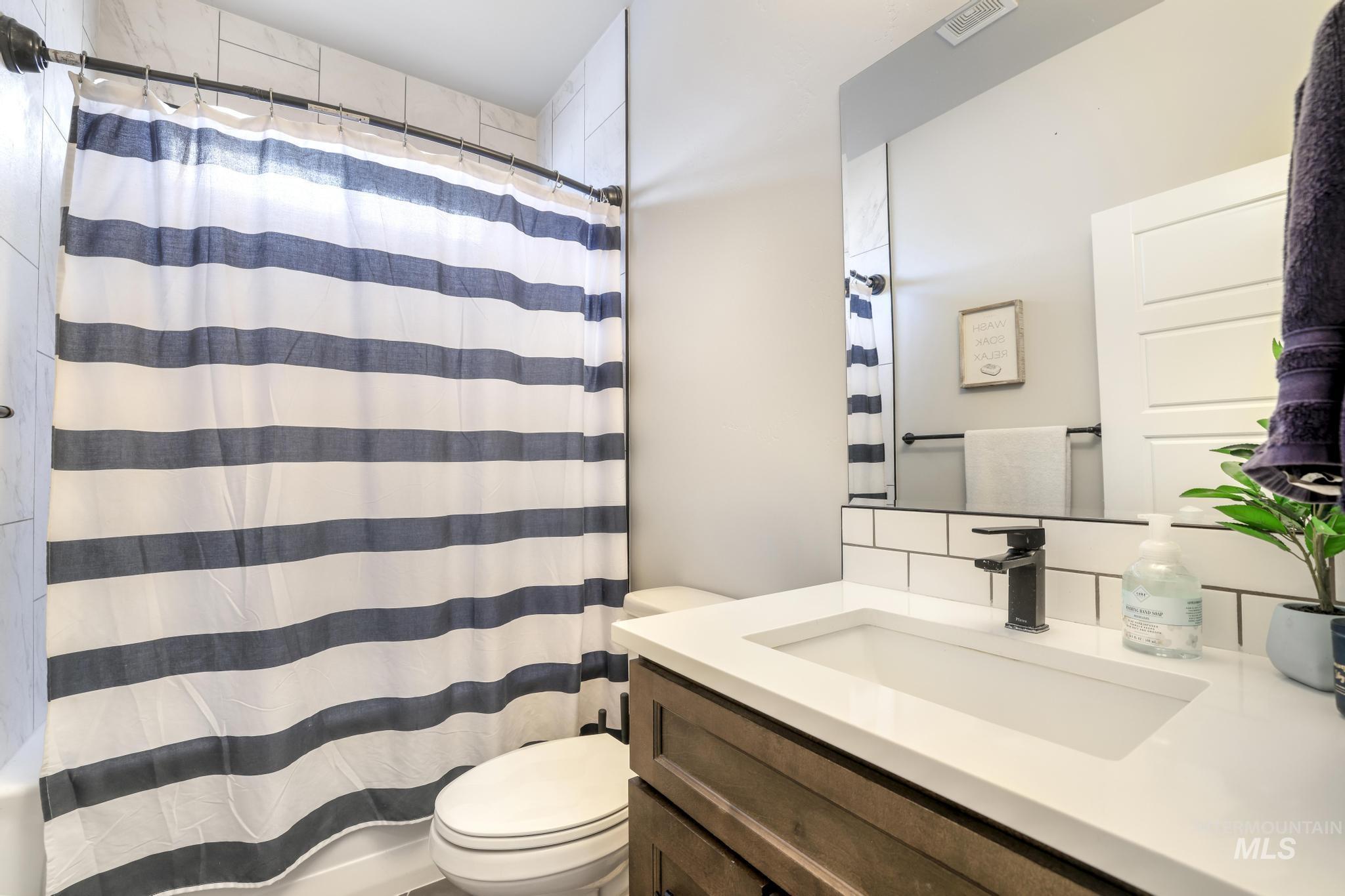 Full bathroom featuring vanity and decorative backsplash