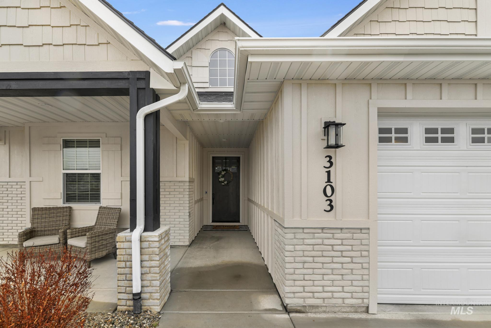 Entrance to property with board and batten siding, brick siding, and covered porch