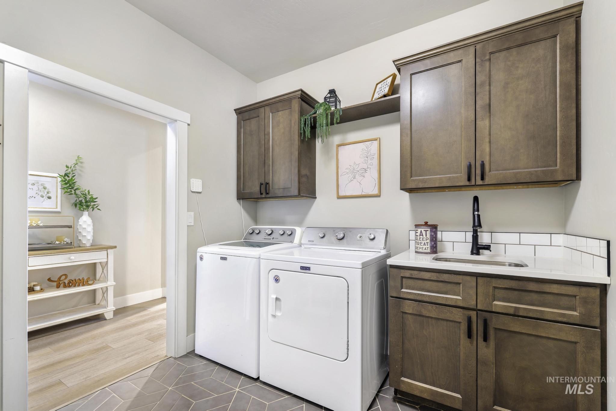 Laundry area with cabinet space, washing machine and clothes dryer, and dark tile patterned flooring