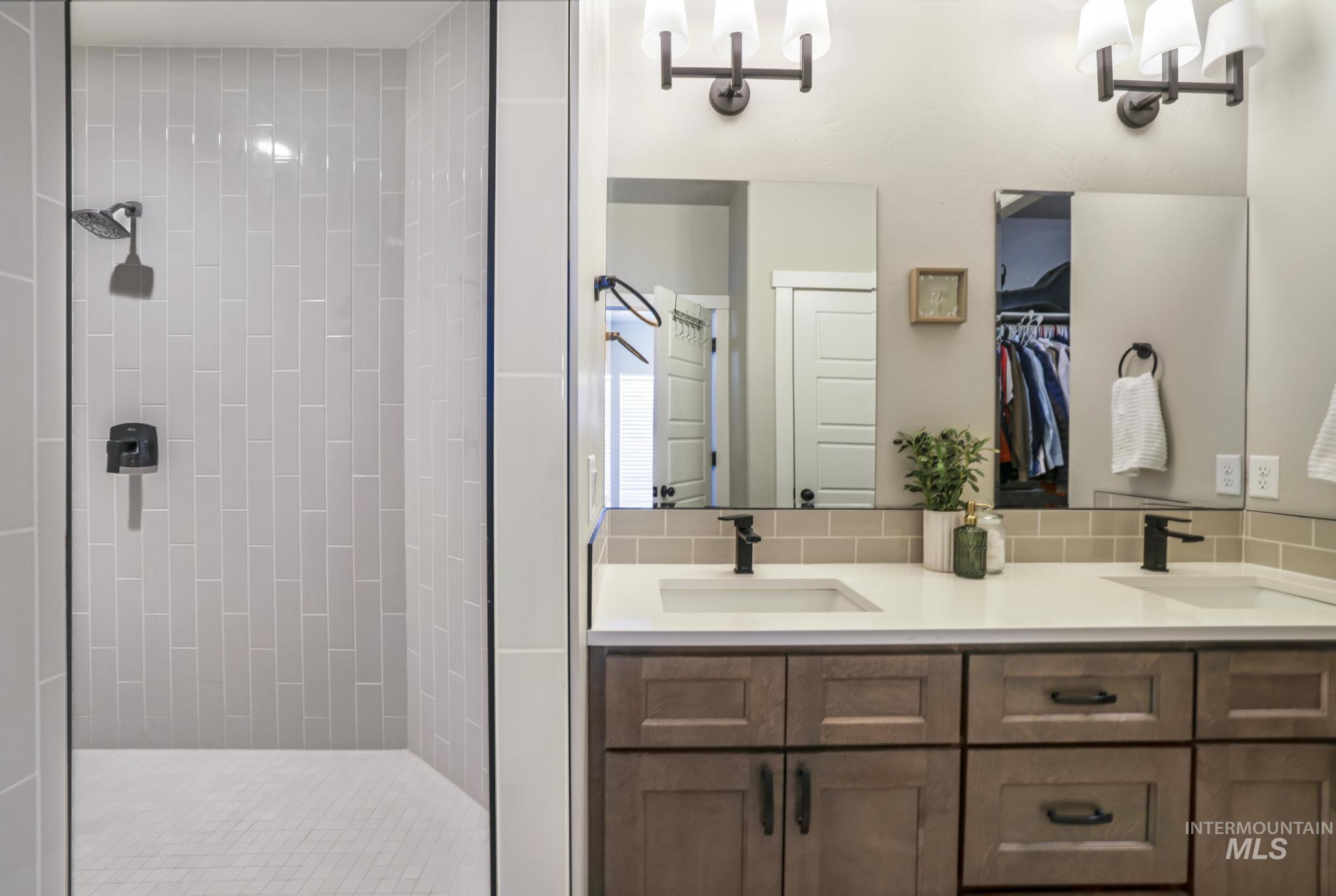 Bathroom with double vanity, a shower stall, and a walk in closet