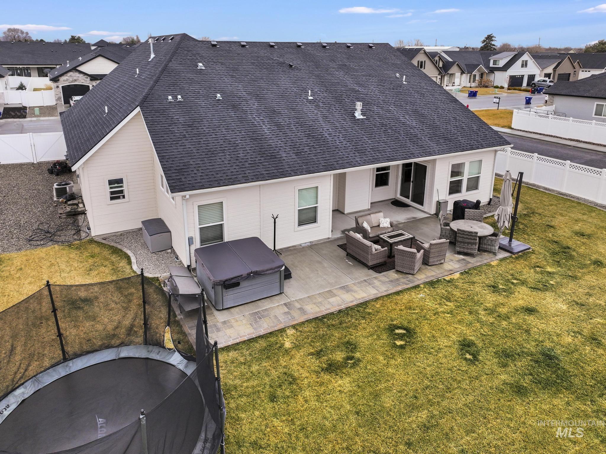 Back of property featuring outdoor furniture, a residential view, a patio area, a fenced backyard, and a trampoline