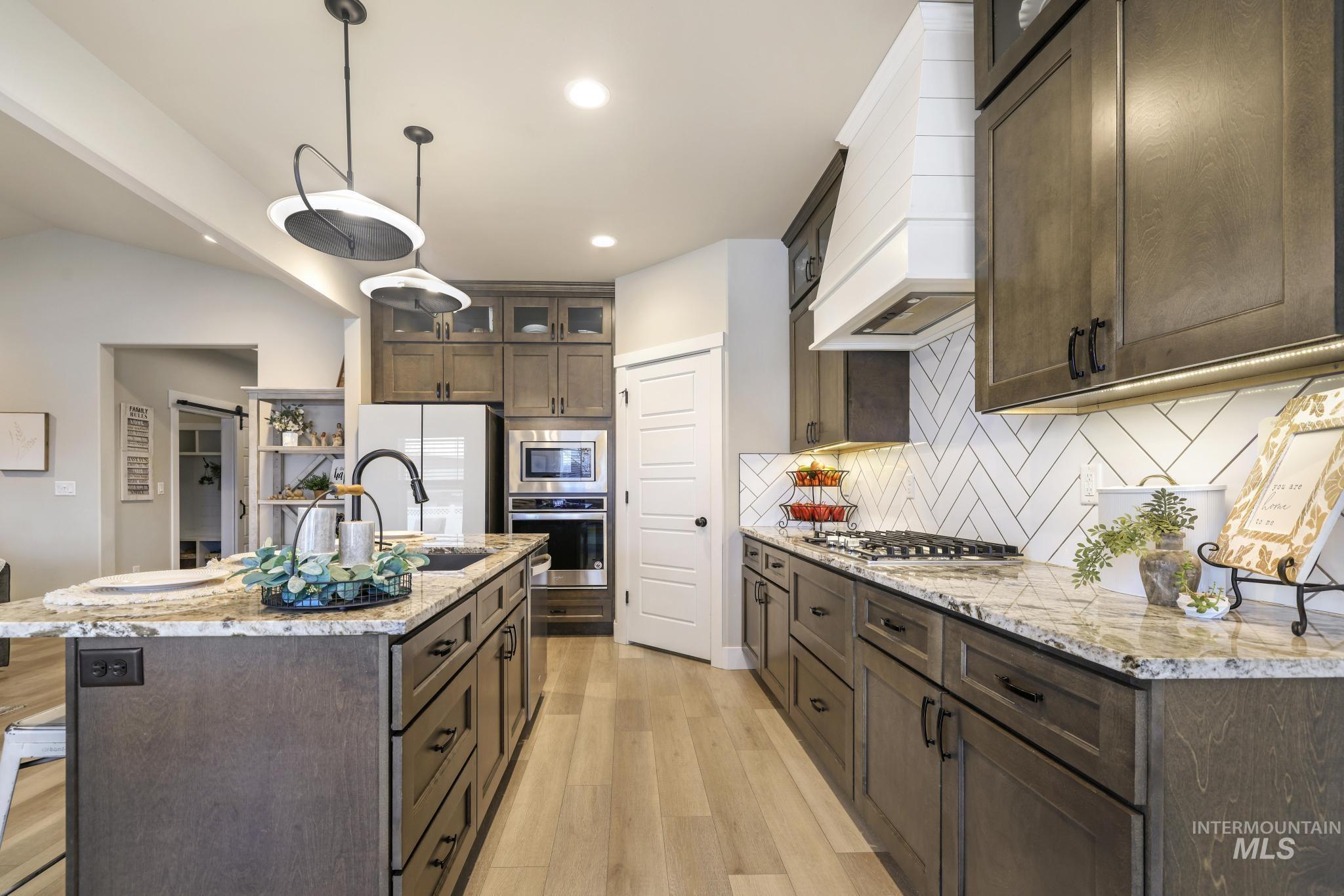 Kitchen featuring glass fronted cabinets, light stone countertops, and dark wood finish cabinets