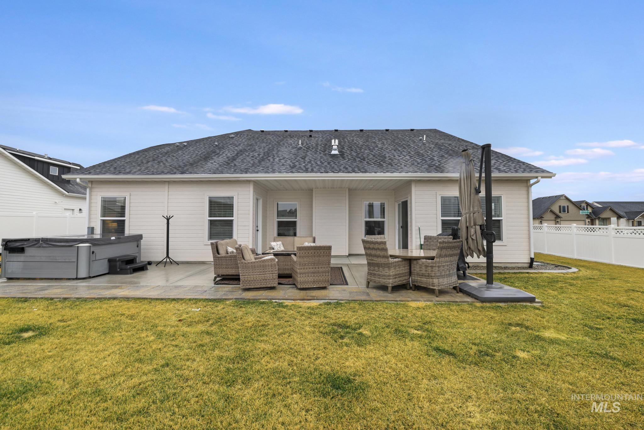 Rear view of house with a hot tub, an outdoor living space, a patio, and roof with shingles