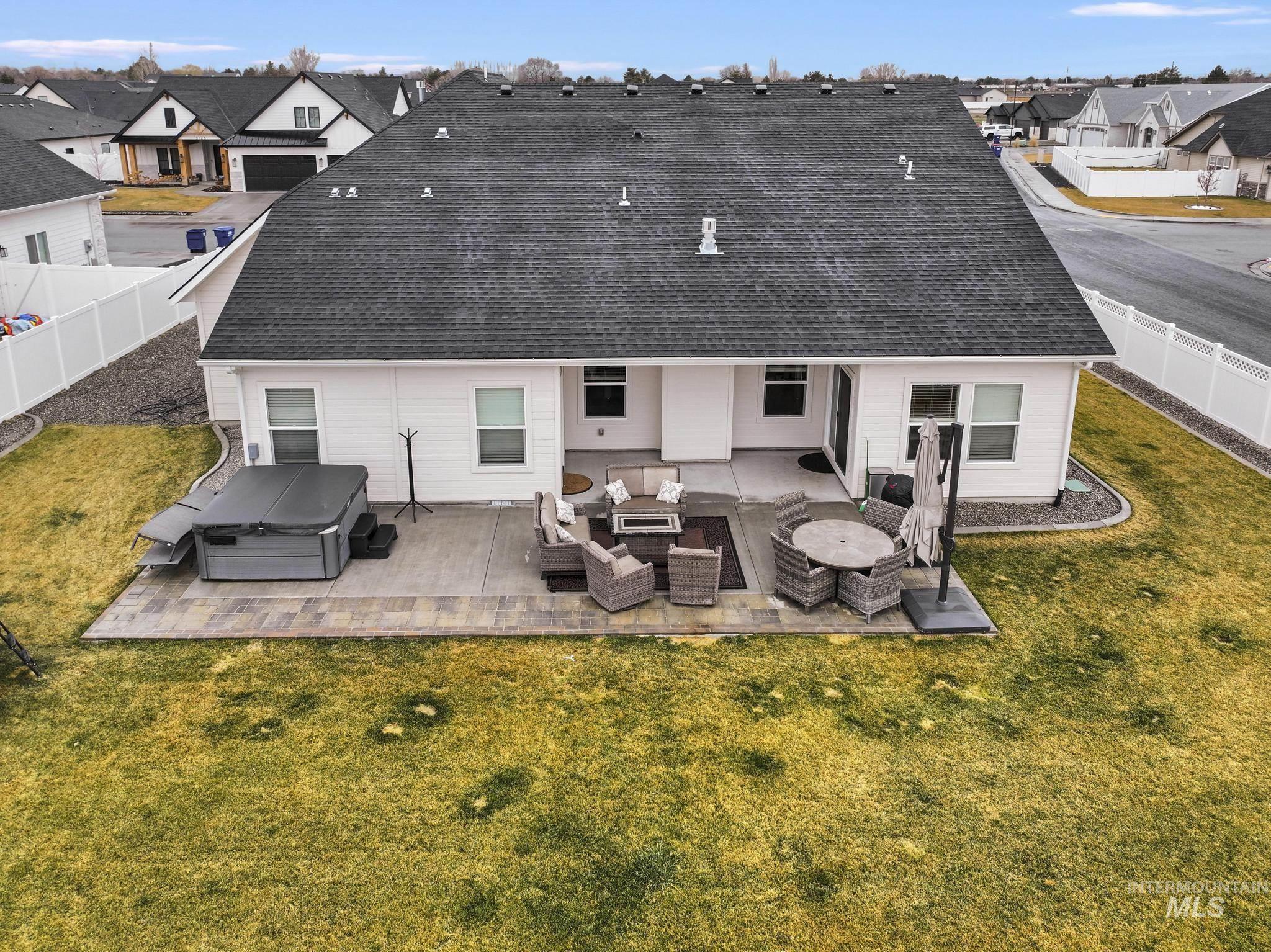 Rear view of property featuring an outdoor hangout area, a residential view, a fenced backyard, a patio, and a hot tub