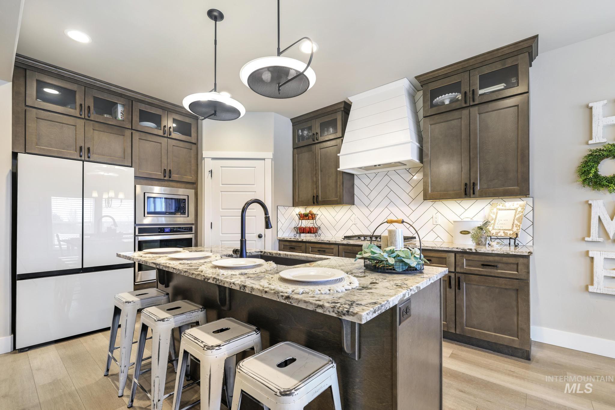 Kitchen featuring stainless steel appliances, light stone counters, and dark wood finish cabinets