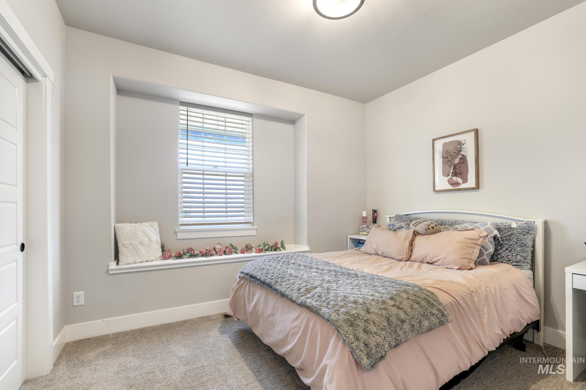 Bedroom with light colored carpet and baseboards