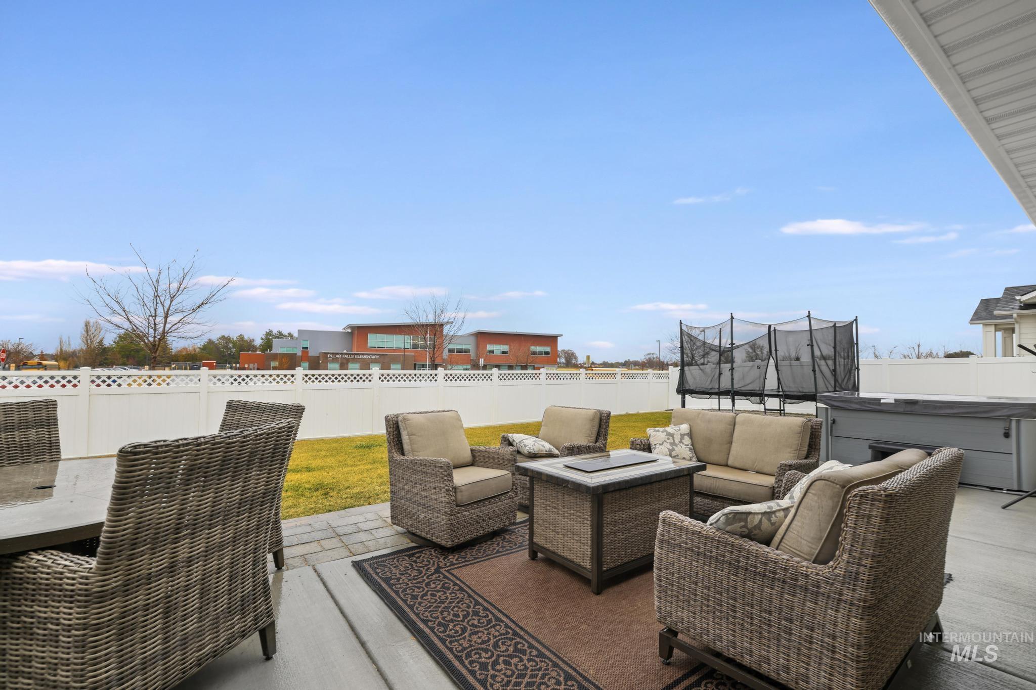 Fenced backyard with a trampoline, a patio area, a hot tub, and outdoor lounge area