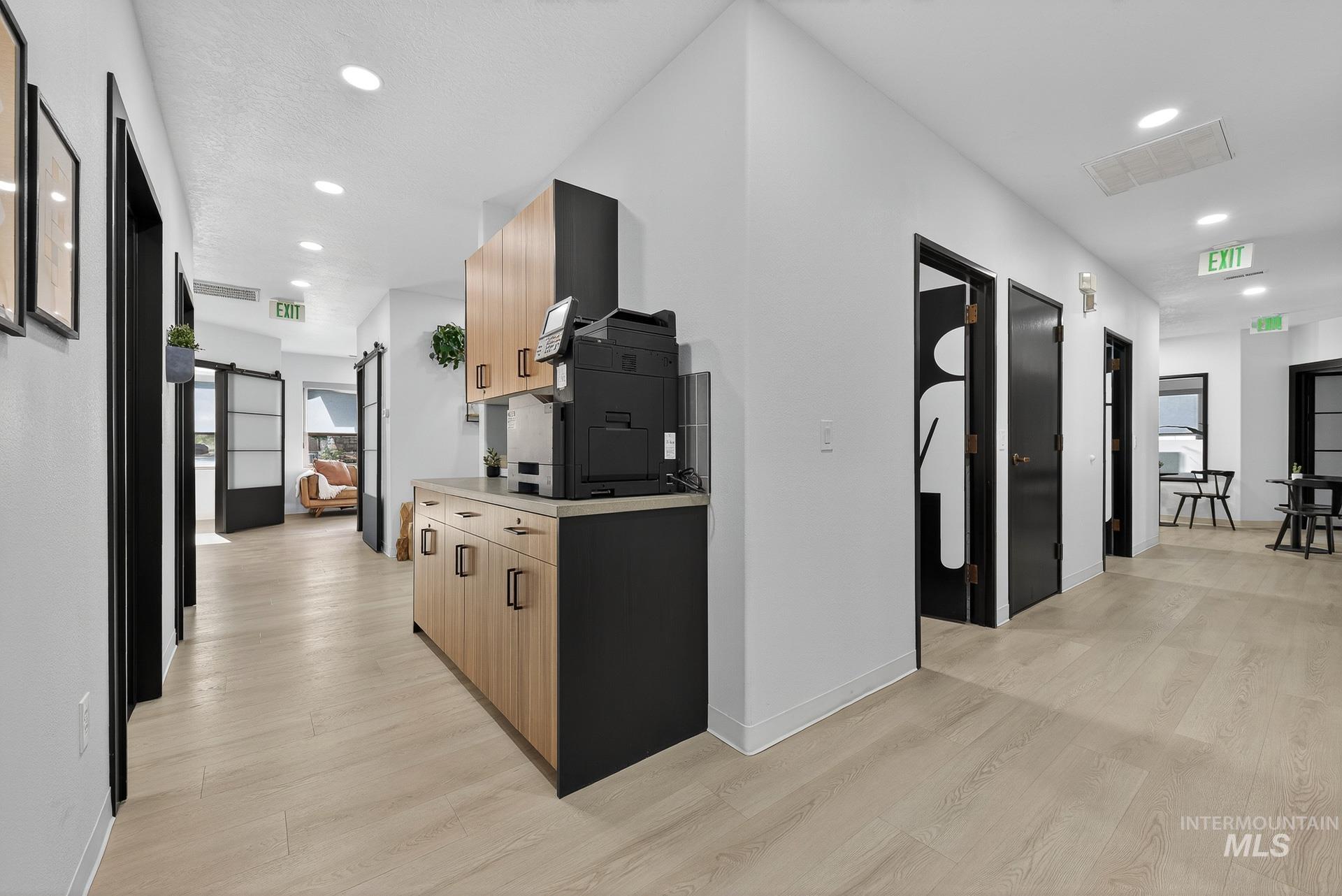 Corridor featuring a barn door, recessed lighting, and light wood-style flooring