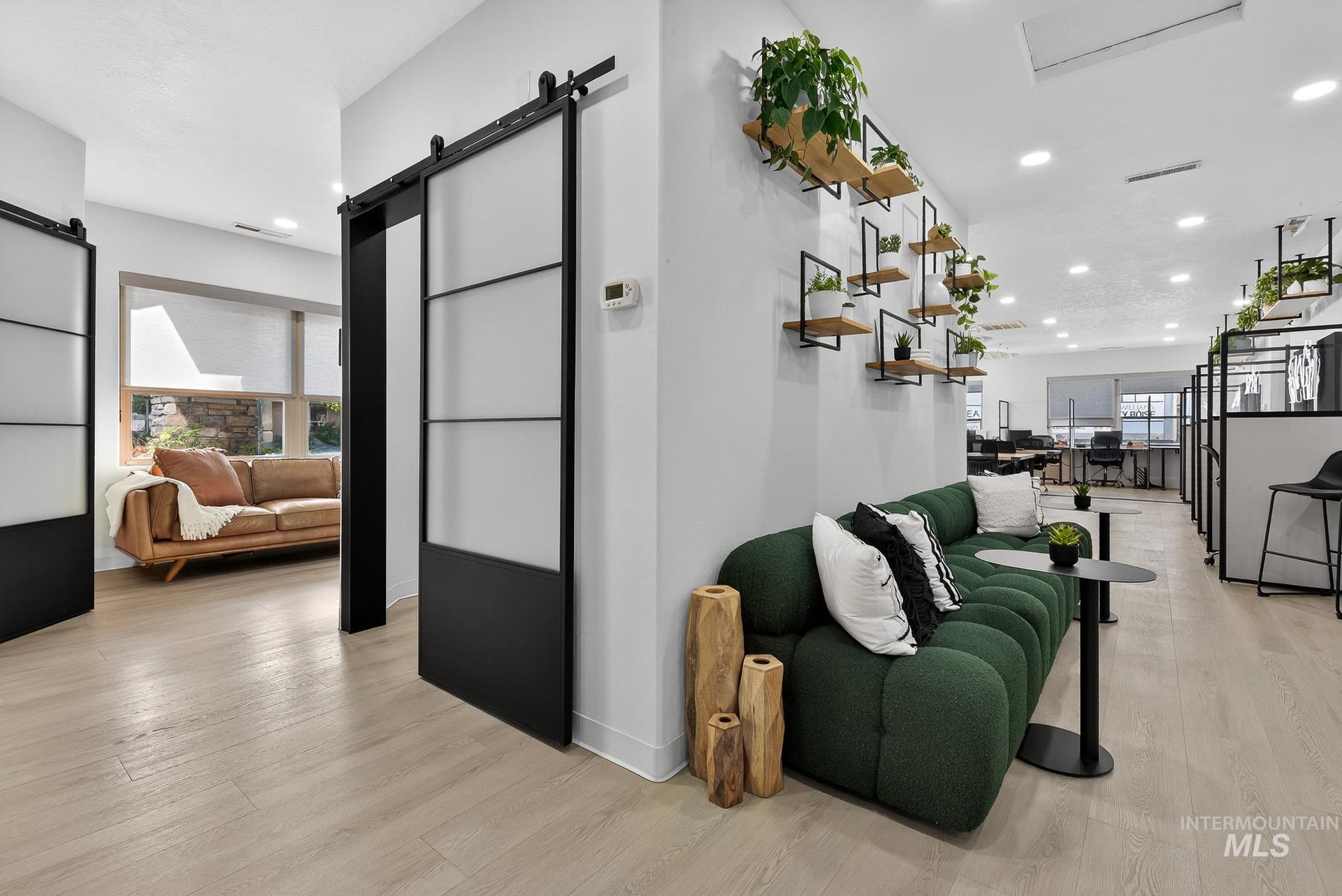 Hallway with a barn door, light wood-style flooring, and recessed lighting