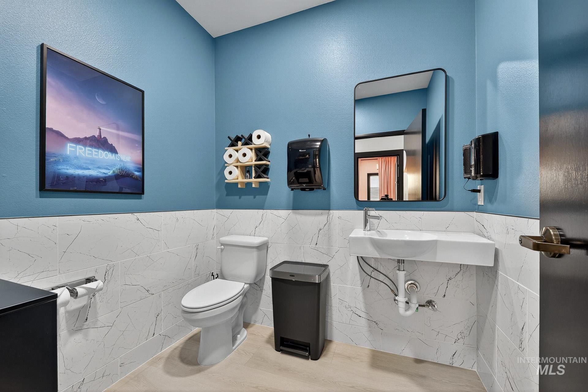 Bathroom featuring tile walls, a wainscoted wall, and wood finished floors