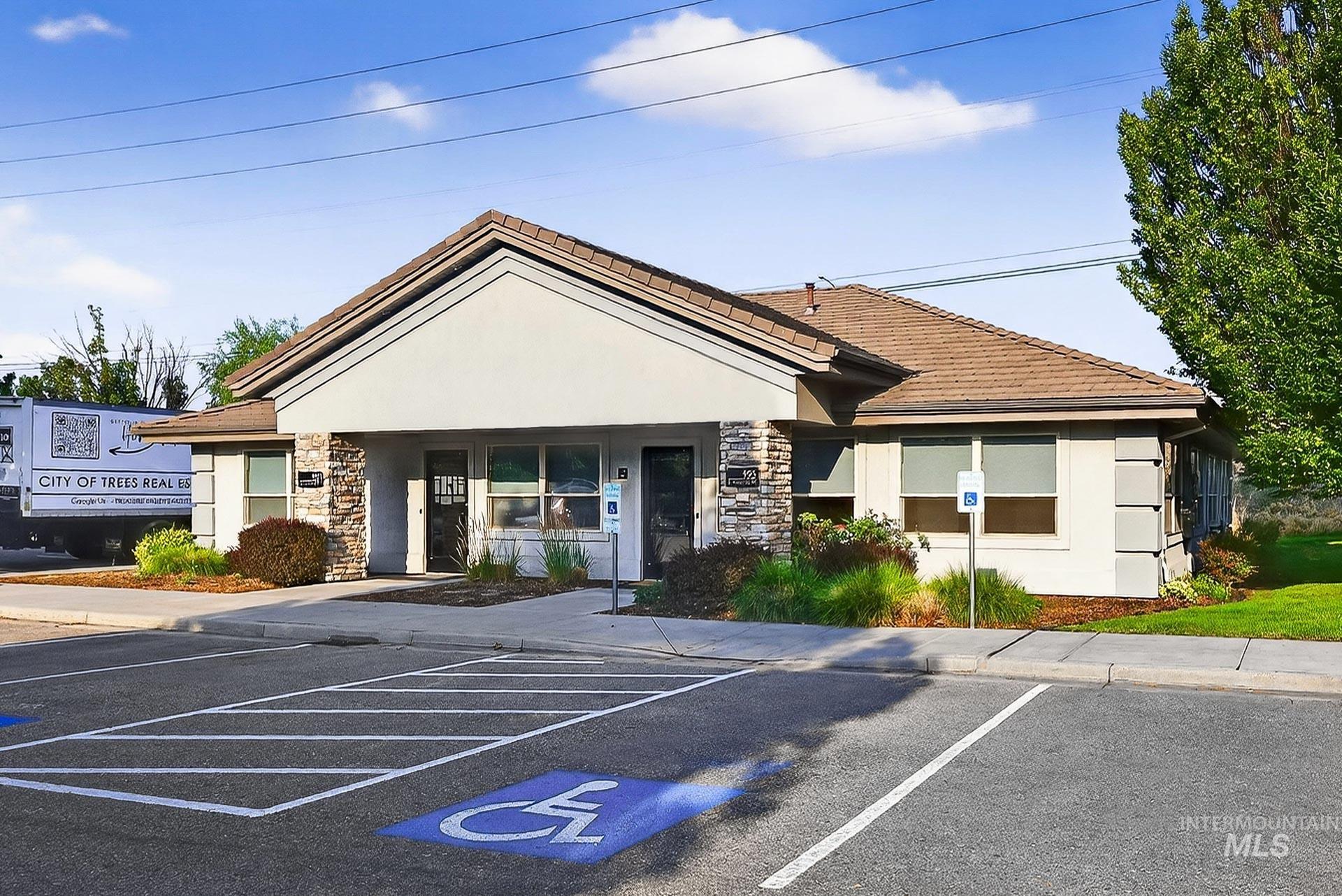 View of front of property featuring stone siding, stucco siding, and uncovered parking