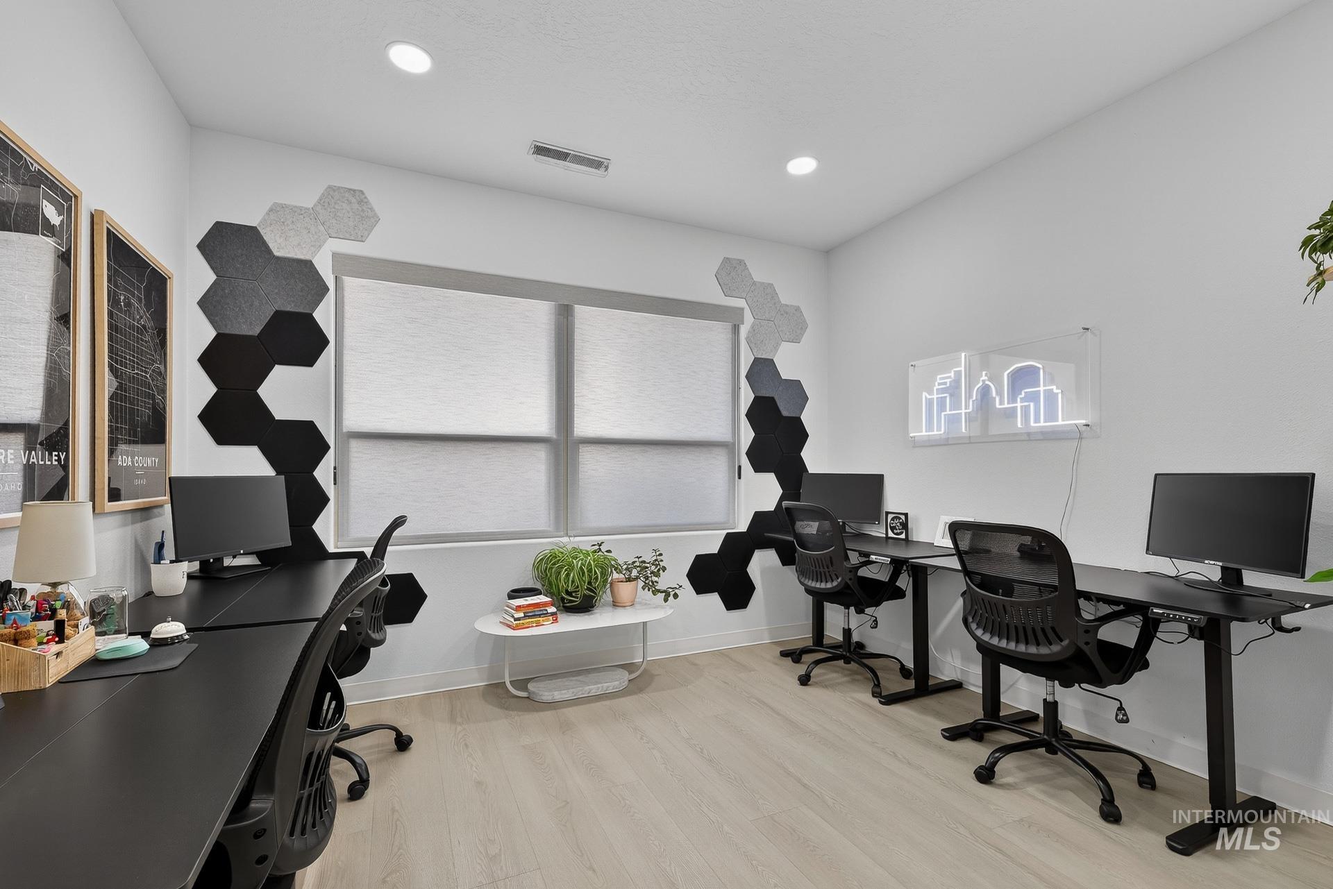 Office area with light wood-style floors and recessed lighting