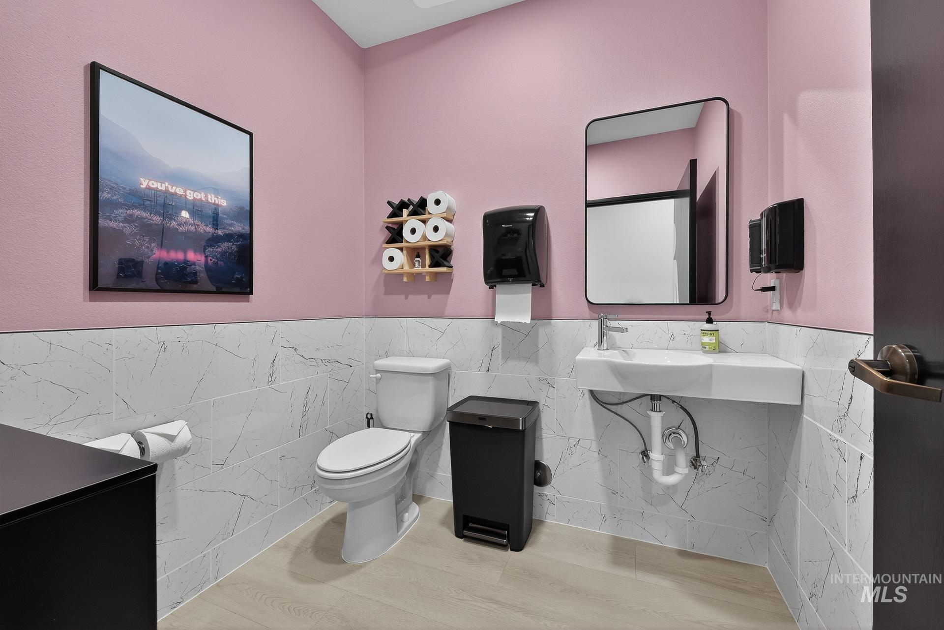 Bathroom with tile walls, wainscoting, and wood finished floors