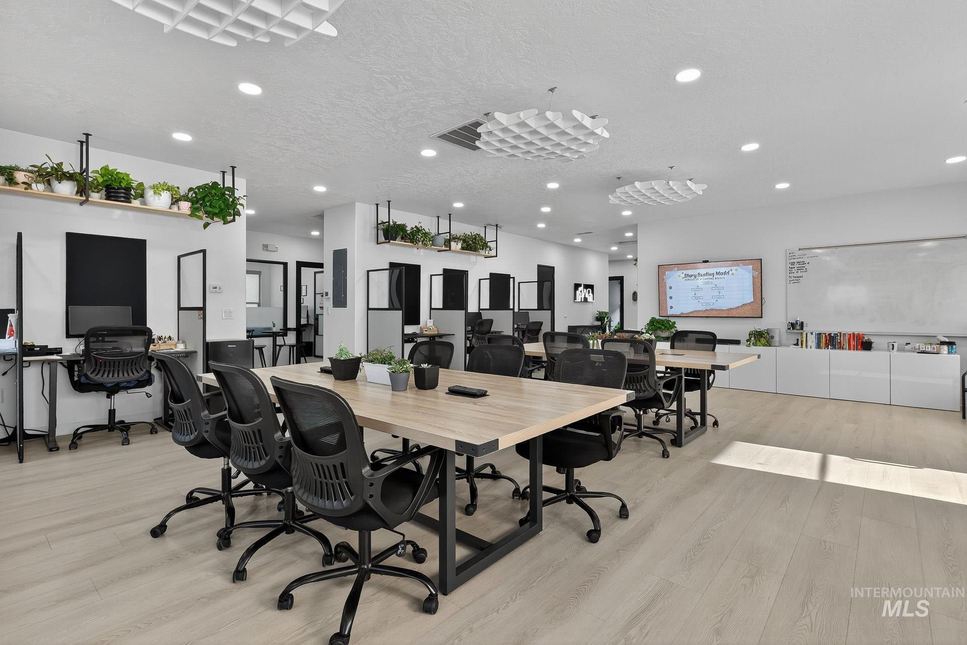 Office area featuring light wood finished floors, a textured ceiling, and recessed lighting