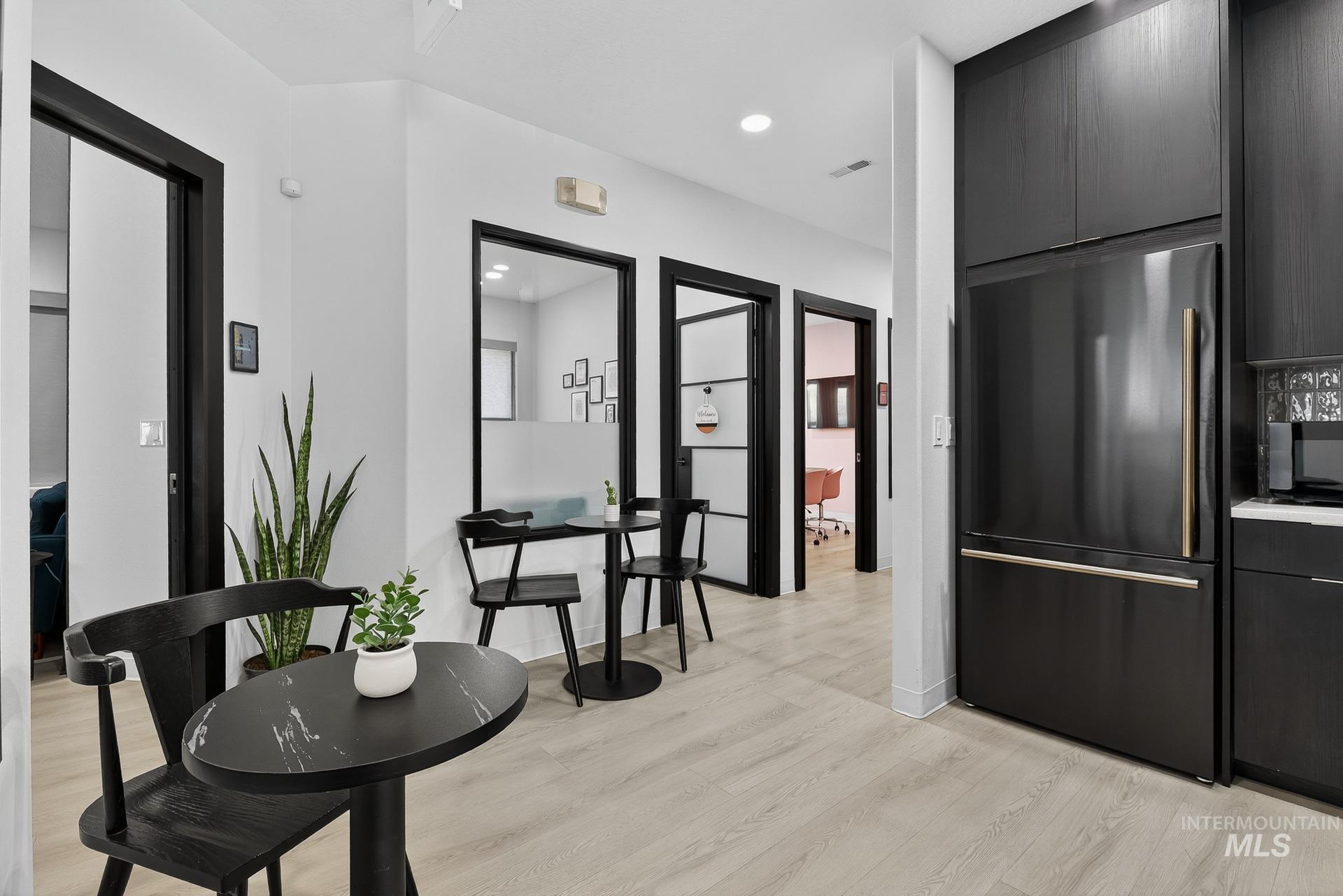 Kitchen with high quality fridge, light wood-type flooring, recessed lighting, black microwave, and modern cabinets