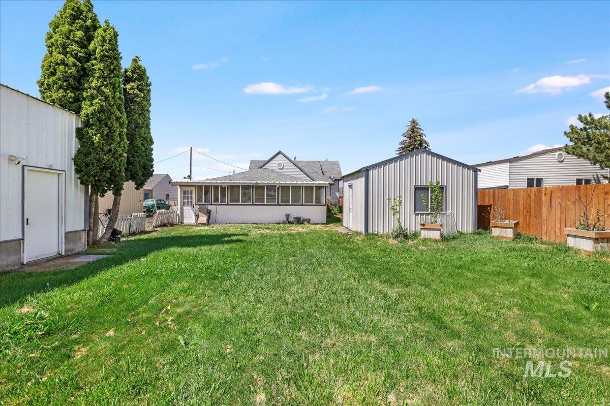 View of yard featuring a sunroom and an outbuilding