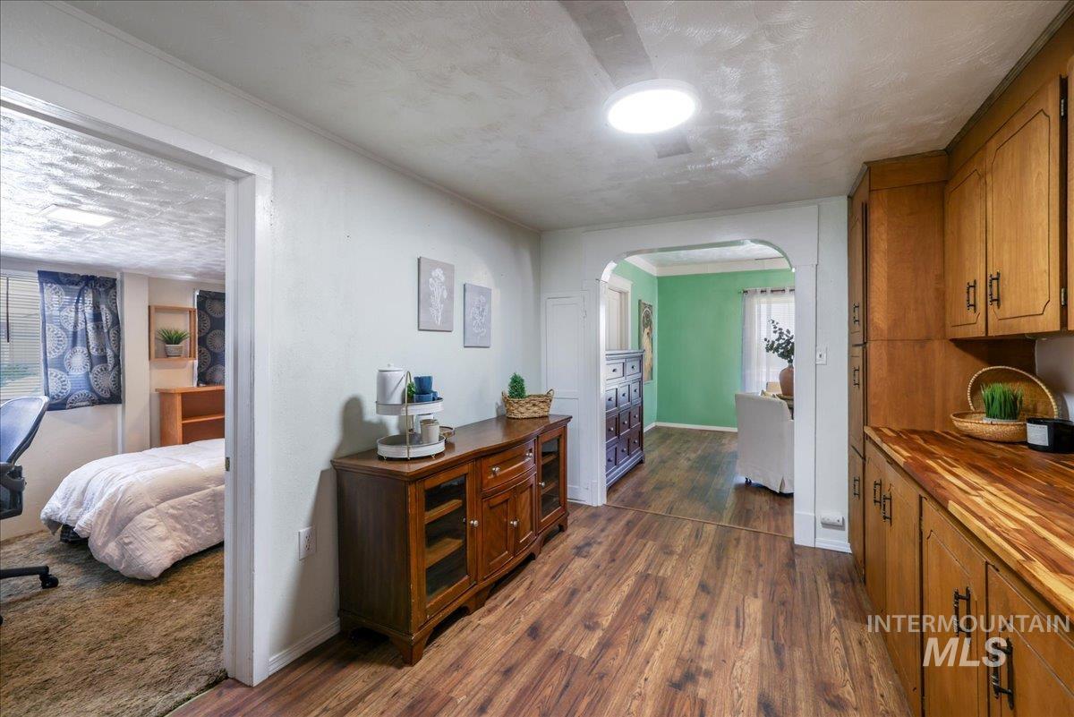 Hall featuring arched walkways, dark wood-type flooring, and a textured ceiling