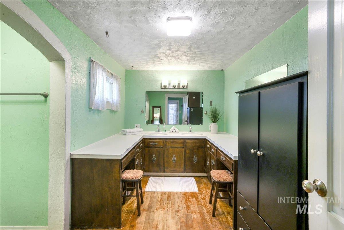 Bathroom with wood finished floors, a textured ceiling, vanity, and a textured wall