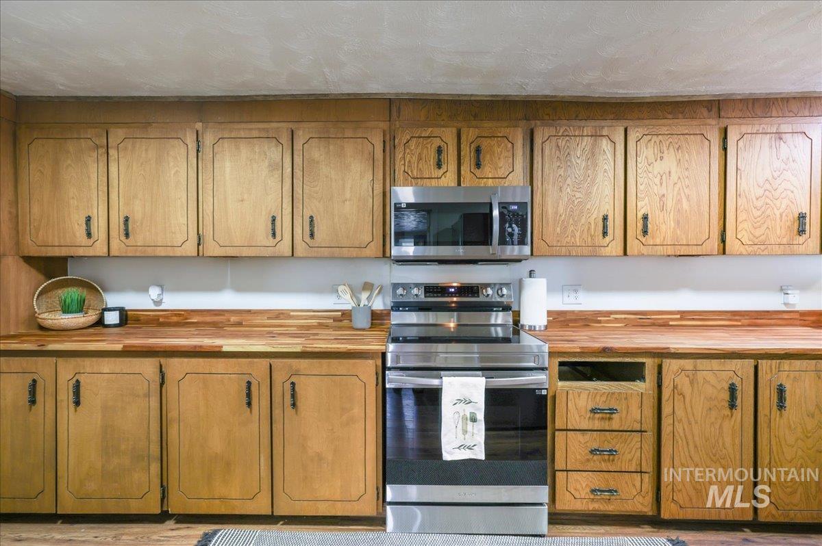Kitchen featuring appliances with stainless steel finishes, wooden counters, and brown cabinets