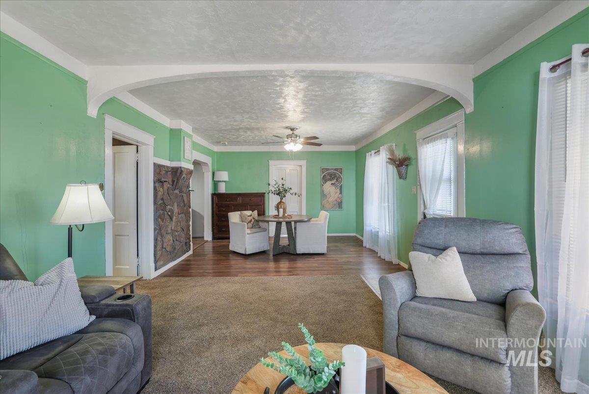 Living room featuring arched walkways, wood finished floors, and a ceiling fan