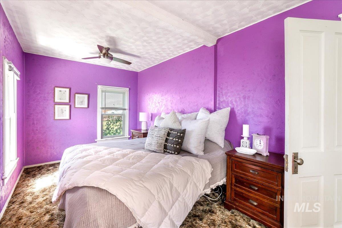 Carpeted bedroom featuring ceiling fan and a textured wall