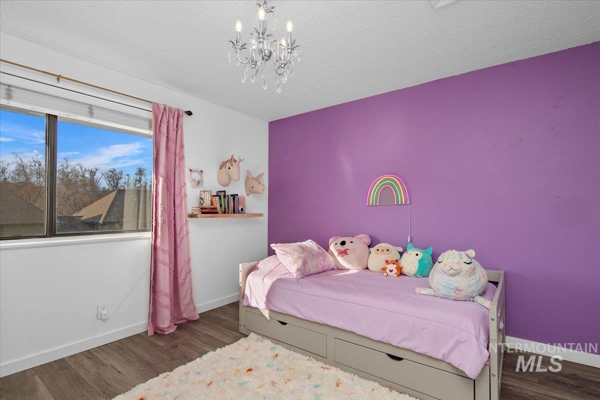 Bedroom with a chandelier, dark wood-style flooring, and a textured ceiling