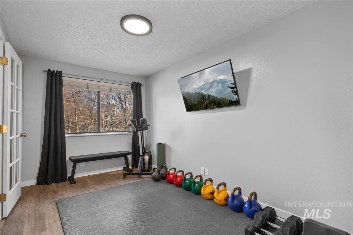 Workout room with a textured ceiling, light wood-style flooring, and french doors