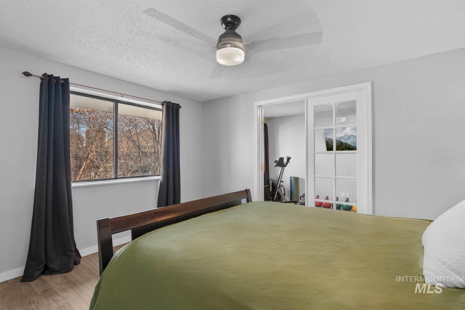 Bedroom featuring a textured ceiling, a ceiling fan, wood finished floors, and a closet