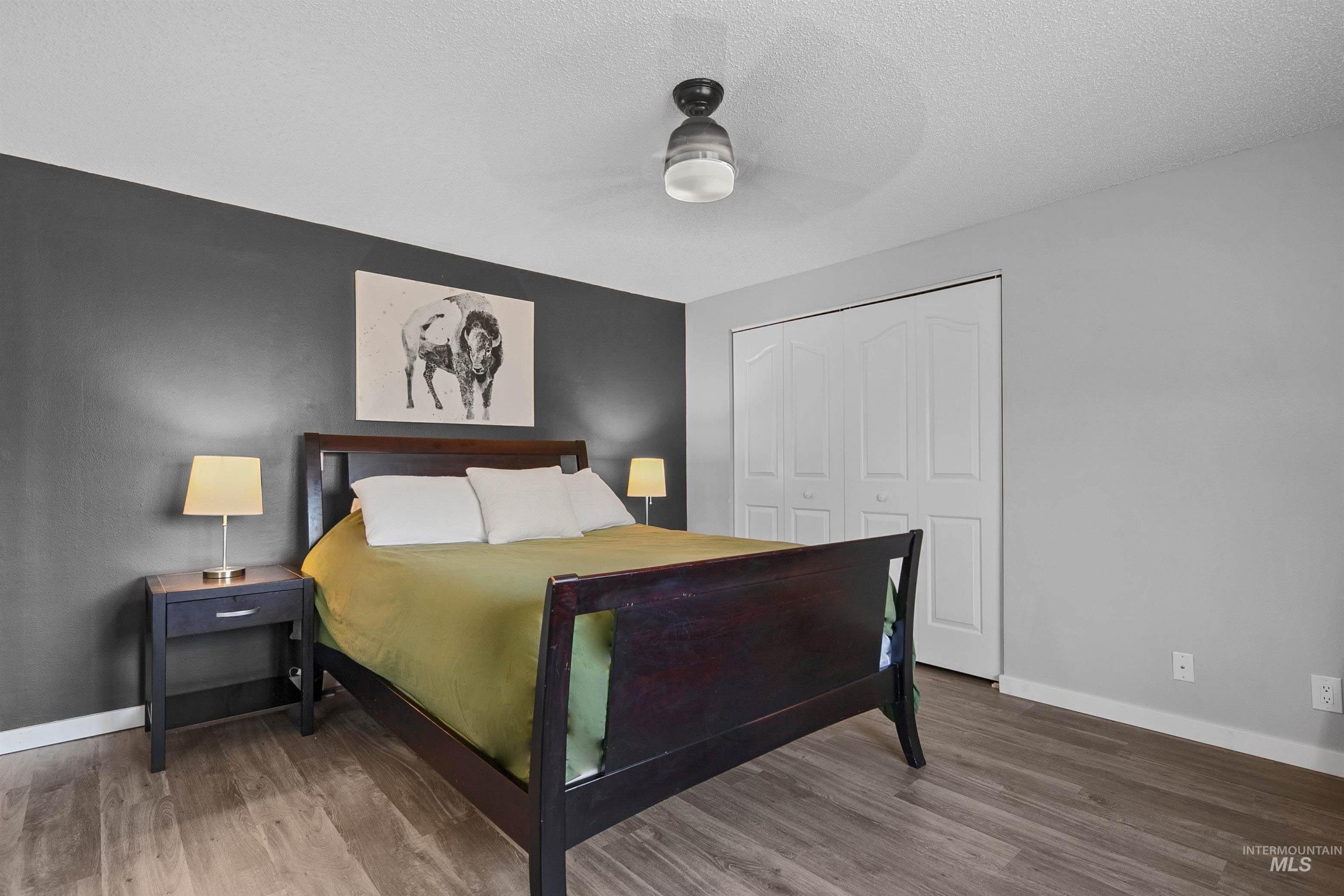 Bedroom featuring a closet, wood finished floors, ceiling fan, and a textured ceiling